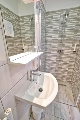 a white bathroom with a sink and a shower at Prenočišča Miklavčič in Nova Vas