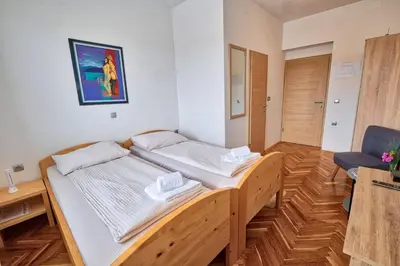 a bedroom with a wooden bed and a chair at Prenočišča Miklavčič in Nova Vas