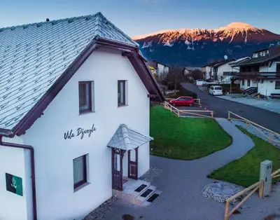 a white building with a mountain in the background at The Jungle Apartments and Rooms (Vila Džungla) in Bled