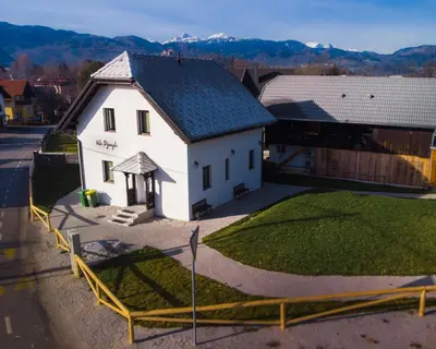 a small white house with a fence around it at The Jungle Apartments and Rooms (Vila Džungla) in Bled