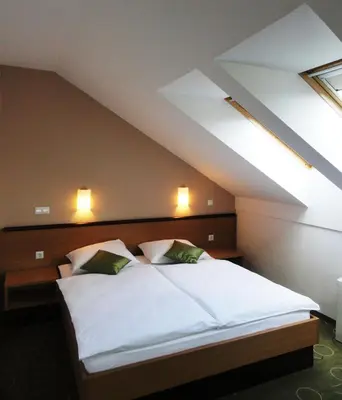 a bedroom with a white bed in a attic at Hotel Bela Krajina in Metlika