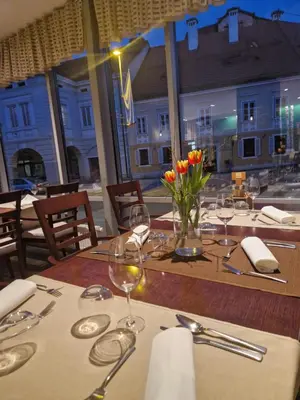 a table with glasses and a vase of flowers on it at Hotel Bela Krajina in Metlika