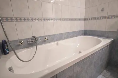 a white bath tub in a tiled bathroom at apartma mojca in Bohinj