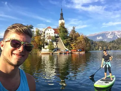 a man is standing on a paddle board in the water at Adventure Cottage with pool and big garden in Bled