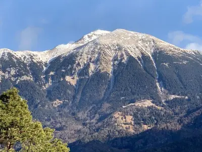 a snow covered mountain with trees in front of it at Adventure Cottage with pool and big garden in Bled