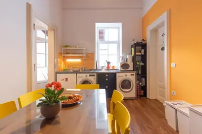 a kitchen with a dining table and yellow chairs at Fluxus Hostel in Ljubljana