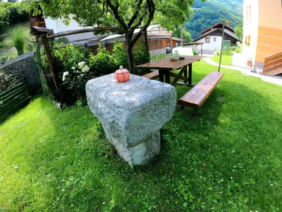 a garden with a bench and a table and a pumpkin at Apartment and Garden house among the mountains in Podbrdo