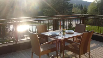 a table and chairs on a balcony with the sun shining at Hotel Rakitna in Rakitna