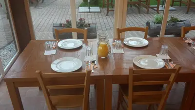 a wooden table with plates and a bottle of orange juice at Hotel Rakitna in Rakitna