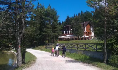 a group of people riding bikes down a road with a house at Hotel Rakitna in Rakitna