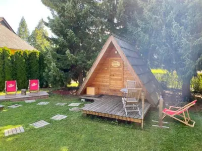 a small wooden cabin with a chair in a yard at Glamping houses J-Max in Bled