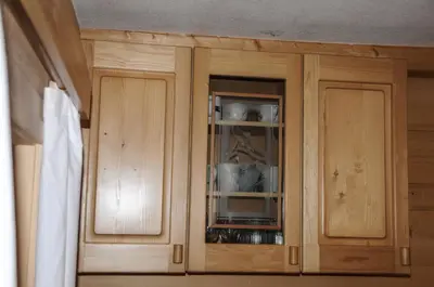 a wooden cabinet with glass doors in a kitchen at Gorska hiška Vogar nad Bohinjskim jezerom in Bohinj