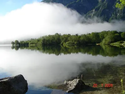 a view of a lake with fog on the water at Apartments Lake Bohinj in Bohinj