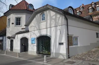 a white building with a gate on the side of it at H2O Hostel in Ljubljana