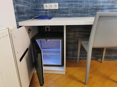 a small refrigerator under a desk with a table at H2O Hostel in Ljubljana