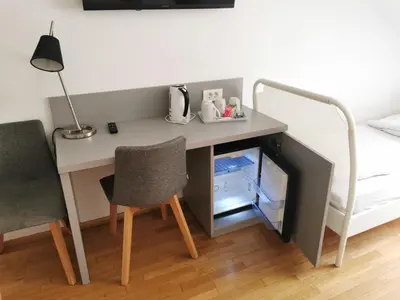 a desk in a bedroom with a bed and a desk with chairs at Rooms Sincere 1830 in Ljubljana