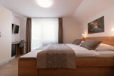 a bedroom with a large bed and a desk at Apartments & Rooms Malej in Bohinj