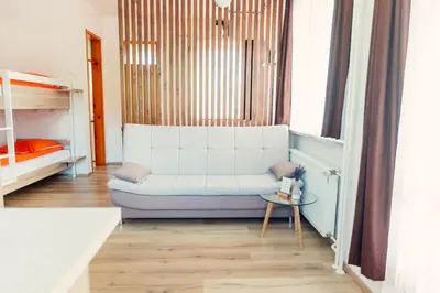 a living room with a white couch and a bed at Frankovič Bed&Breakfast in Vinica