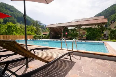 a bench with an umbrella next to a swimming pool at Tourist Farm Zelinc in Cerkno