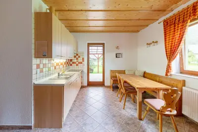 a kitchen with a wooden table and a wooden ceiling at APARTMA KOŠNIK in Bohinj