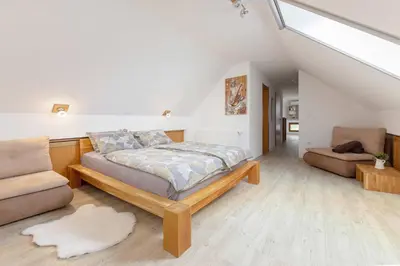 a bedroom with a bed and a couch and a chair at APARTMA KOŠNIK in Bohinj