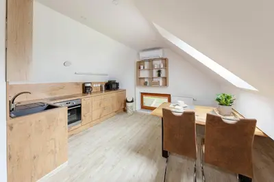 an attic kitchen with a wooden table and chairs at APARTMA KOŠNIK in Bohinj