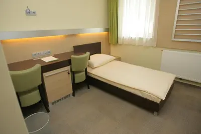 a small room with a bed and a desk with chairs at Hotel Center Pokljuka in Goreljek
