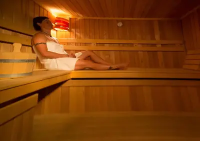 a woman is sitting in a sauna at Hotel Center Pokljuka in Goreljek