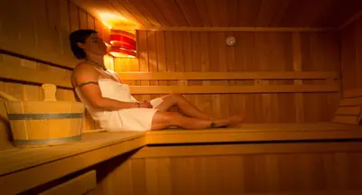 a woman is sitting in a sauna at Hotel Center Pokljuka in Goreljek