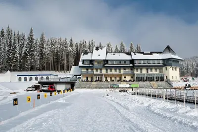 a large building in the snow with snow covered trees at Hotel Center Pokljuka in Goreljek