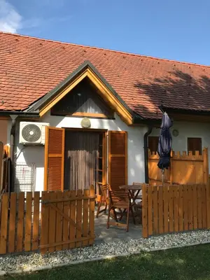 a house with a wooden fence and a table and an umbrella at Apartma, Prekmurska vas, Trobentica 32 in Moravske Toplice
