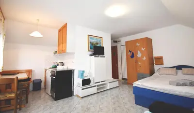 a bedroom with a bed and a desk and a kitchen at Apartment Kolman in Bohinj
