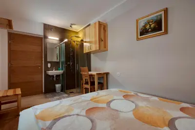 a bedroom with a large bed and a bathroom at Rooms Pevc & Hostel Ljubno ob Savinji in Ljubno