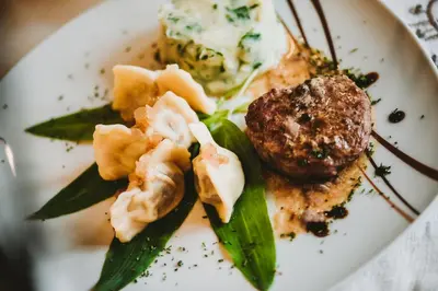 a plate of food with meat and vegetables on it at Rooms Pevc & Hostel Ljubno ob Savinji in Ljubno