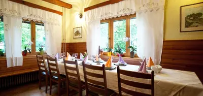 a dining room with a long table with chairs and windows at Rooms Pevc & Hostel Ljubno ob Savinji in Ljubno