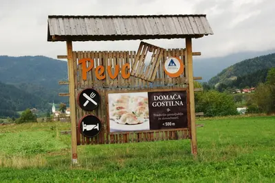 a sign for a restaurant in a field at Rooms Pevc & Hostel Ljubno ob Savinji in Ljubno