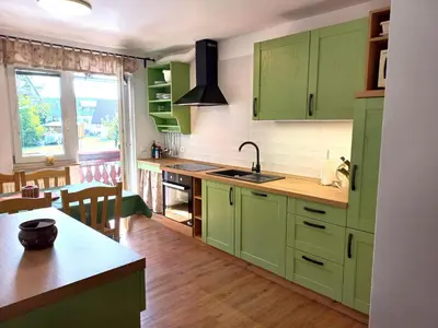 a kitchen with green cabinets and a kitchen island at Apartments Markež in Bohinj