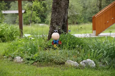 a toy in the grass next to a tree at Apartments Markež in Bohinj