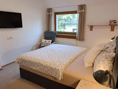 a bedroom with a bed and a tv and a chair at Apartments Markež in Bohinj