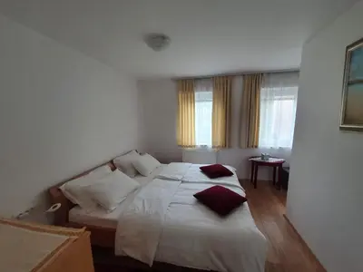 a bedroom with a bed with white sheets and red pillows at Apartma Meta in Radovljica