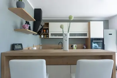 a kitchen with a wooden counter with white chairs at Nature View House with Sauna in Tolmin