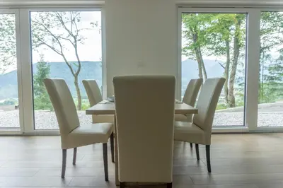 a dining room with a table and chairs and windows at Nature View House with Sauna in Tolmin