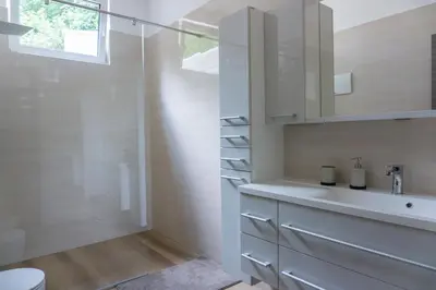 a white bathroom with a sink and a shower at Nature View House with Sauna in Tolmin