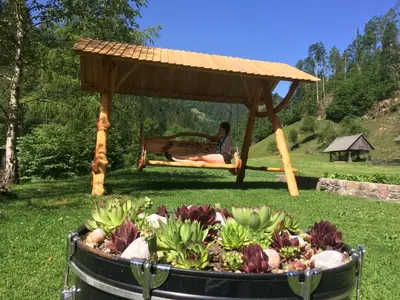 a person sitting in a gazebo with a bunch of flowers at Turistična kmetija Čerček in Solčava
