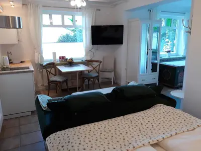 a living room with a couch and a kitchen with a table at Pletna Lake View Apartment (Ground Floor) in Bled