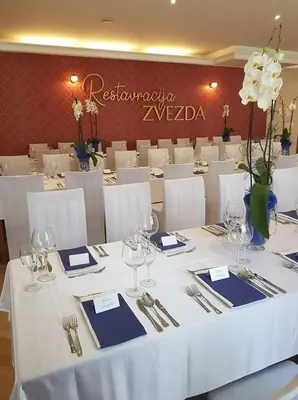 a table with white table cloth and wine glasses at Hotel Zvezda in Murska Sobota