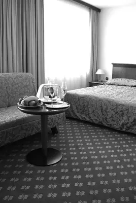 a hotel room with a table and two beds at Hotel Zvezda in Murska Sobota