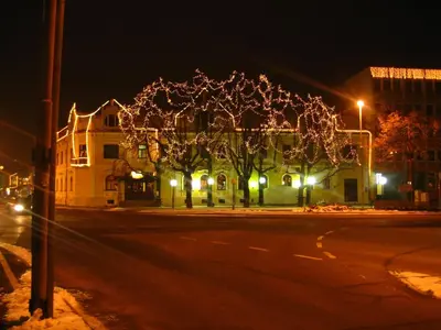a street at night with a tree with christmas lights at Hotel Zvezda in Murska Sobota