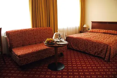 a hotel room with a bed and a chair and a table at Hotel Zvezda in Murska Sobota