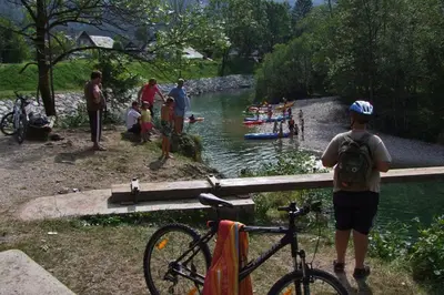 a boy standing next to a bike next to a river at Farmhouse Soklic in Bohinj